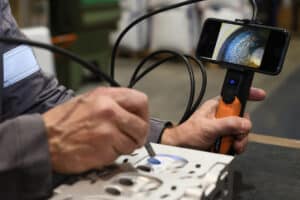 Premium Steel Abrasives Performance - Technician inspecting cleaning performance in a hole using a mobile phone and borescope